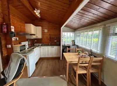 a kitchen with wooden ceilings and a wooden table and chairs at Snug and cosy log cabin. in Trawsfynydd