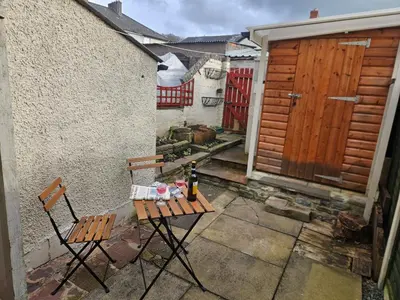 a patio with two chairs and a table and a door at Rhif Deg in Brecon