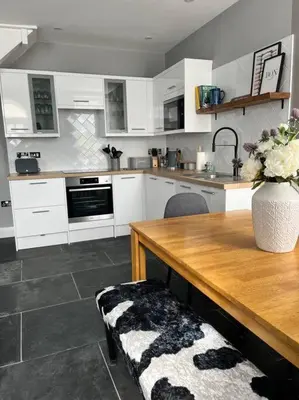 a kitchen with a wooden table and a vase of flowers at Isfryn, holiday home in Aberdyfi in Aberdyfi
