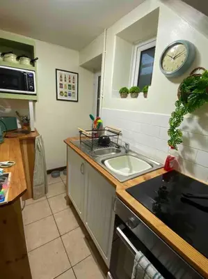 a kitchen with a sink and a clock on the wall at Maytree Cottage. Compact home in Mid Wales. in Llanrhaeadr-ym-Mochnant