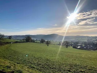 a green field with the sun in the sky at Maytree Cottage. Compact home in Mid Wales. in Llanrhaeadr-ym-Mochnant
