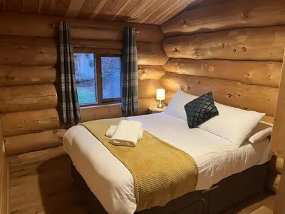 a bedroom with a bed in a log cabin at Mountain Edge Resort Lodge 2 with Hot Tub in Church Stretton