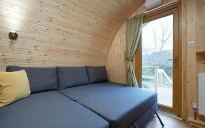 a blue couch in a room with a window at Mountain Edge Resort Mega pod 1 with Hot Tub in Church Stretton