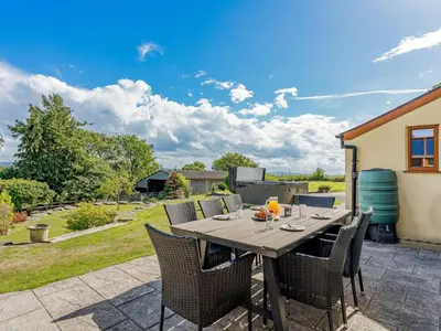 a wooden table with chairs on a patio at 5 Bed in Aberystwyth oc-58889 in Llanrhystyd