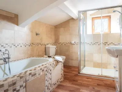 a bathroom with a tub and a shower and a sink at 5 Bed in Aberystwyth oc-58889 in Llanrhystyd