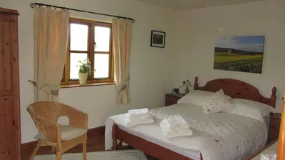 a bedroom with a bed and a chair and a window at The Long Barn in Church Stretton
