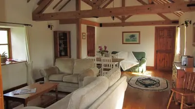a living room with a couch and chairs and a table at The Long Barn in Church Stretton