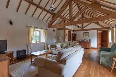 a living room with two couches and a tv at The Long Barn in Church Stretton