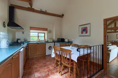 a kitchen with a table and chairs in a room at The Long Barn in Church Stretton