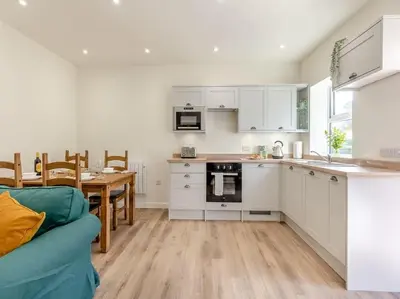 a kitchen with white cabinets and a table with a blue couch at The Barrels at Leintwardine in Leintwardine