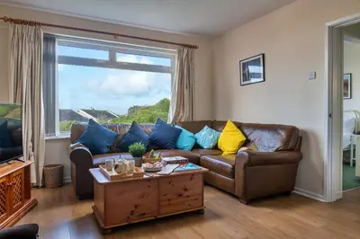 a living room with a brown leather couch and a window at Finest Retreats - 37 Bro Enddwyn in Dyffryn
