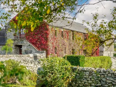 a building covered in ivy with a stone wall at 1 Bed in Dyffryn Ardudwy oc-89777 in Dyffryn