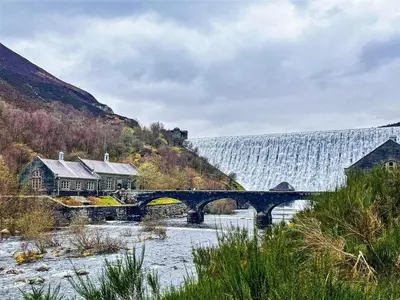 a bridge over a river with a waterfall in the background at 1 Bed in Rhayader oc-90285 in Saint Harmon