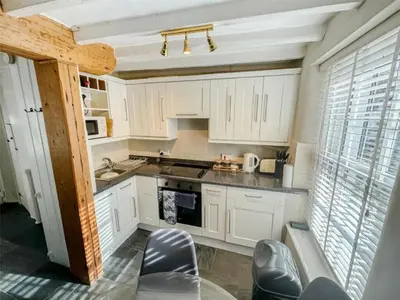 a kitchen with white cabinets and appliances and chairs at The Retreat - 2 bed cottage in Aberdovey in Aberdyfi