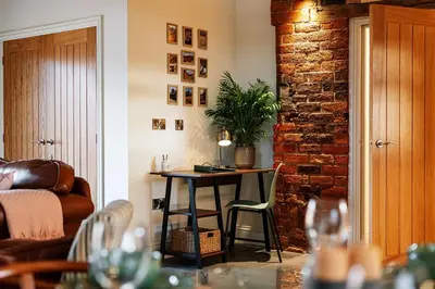 a living room with a table and a brick wall at Pigeon House - Unique Barn with private garden, hot tub and wood burner in Shrewsbury