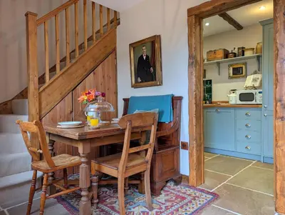 a dining room with a wooden table and chairs at Romantic Country Cottage with log burner, garden patio, outdoor tub and country views- Brecon Beacons National Park in Llangadog