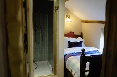 a bathroom with a shower and a bed and a tub at Romantic Country Cottage with log burner, garden patio, outdoor tub and country views- Brecon Beacons National Park in Llangadog