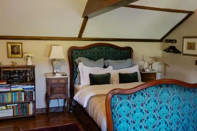 a bedroom with a bed and a night stand with a lamp at Romantic Country Cottage with log burner, garden patio, outdoor tub and country views- Brecon Beacons National Park in Llangadog