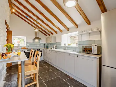 a kitchen with white cabinets and a table and chairs at 6 Bed in Harlech oc-91546 in Harlech