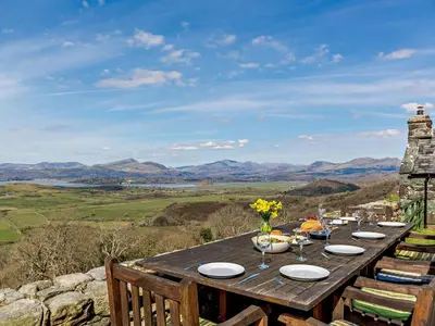 a wooden table with plates and flowers on it at 6 Bed in Harlech oc-91546 in Harlech