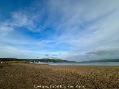 a sandy beach with a blue sky and the ocean at Little Curlew, Ynyslas, Borth in Borth