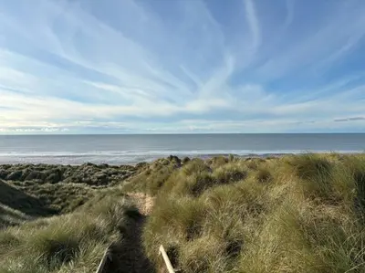 a path to the beach with the ocean in the background at Little Curlew, Ynyslas, Borth in Borth
