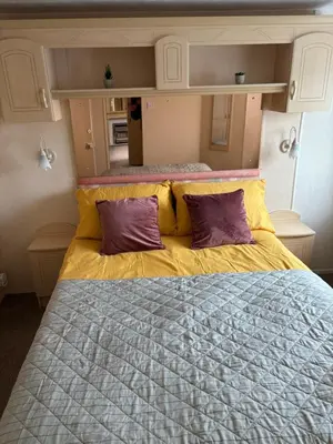 a large bed with two purple pillows on it at Haven on the Hill 2 Bed Caravan with Town Views of Aberystwyth F7 in Aberystwyth