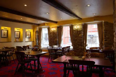 a restaurant with wooden tables and chairs and windows at The Kings Head Inn in Llandovery