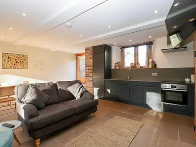 a living room with a couch and a kitchen at Barn Cottage in Leominster