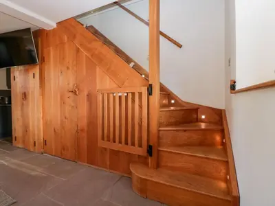 a staircase in a house with wooden walls and a television at Barn Cottage in Leominster