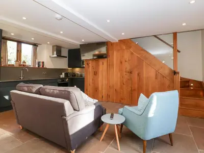 a living room with a couch and two chairs at Barn Cottage in Leominster