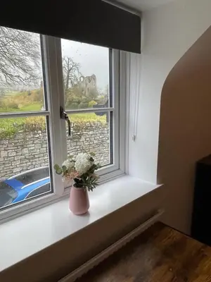 a vase with flowers sitting on a window sill at Beech Cottage with Clun Castle View in Clun