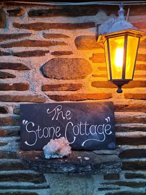 a sign on a brick wall with a sign for the stone coffee at Glan Y Morfa Bach The Stone Cottage in Tywyn