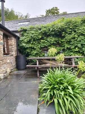 a wooden bench sitting in front of a building at Glan Y Morfa Bach The Stone Cottage in Tywyn