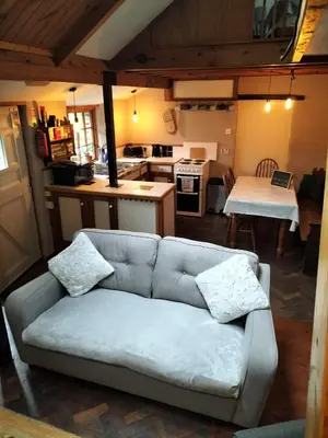 a living room with a couch and a kitchen at Glan Y Morfa Bach The Stone Cottage in Tywyn
