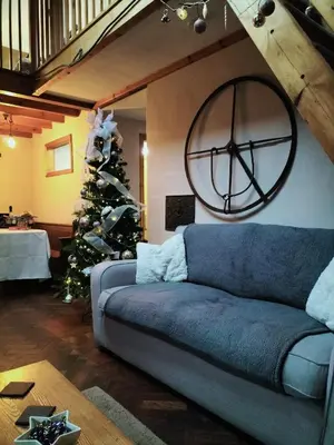 a living room with a blue couch and a christmas tree at Glan Y Morfa Bach The Stone Cottage in Tywyn