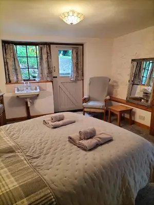 a bedroom with a bed with two towels on it at Glan Y Morfa Bach The Stone Cottage in Tywyn