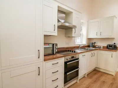 a kitchen with white cabinets and a stove top oven at Afonwy House in Rhayader