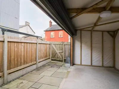 an empty garage with a fence and a red house at Afonwy House in Rhayader