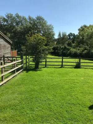 a wooden fence in front of a grass field at The Nut House - Squirrel Lane Lodges Ludlow in Ludlow