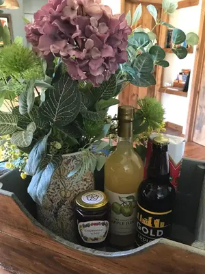 a basket with two bottles of wine and a flower at The Nut House - Squirrel Lane Lodges Ludlow in Ludlow