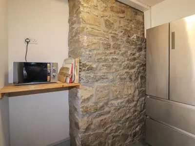 a kitchen with a stone wall and a microwave on a shelf at Wayside House in Craven Arms