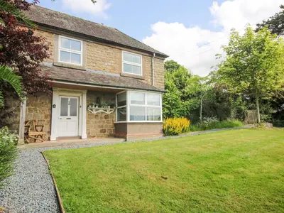 a brick house with a white door and a yard at Wayside House in Craven Arms