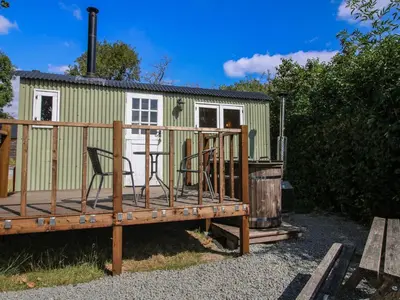 a small green trailer with a chair on a deck at Aston - Shepherd Hut in Craven Arms