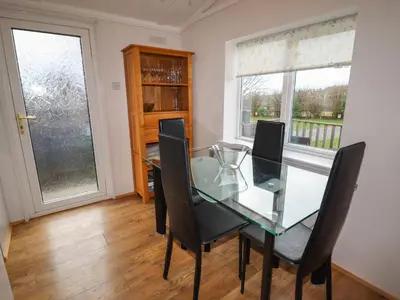 a dining room with a glass table and chairs at Wayside Lodge in Craven Arms