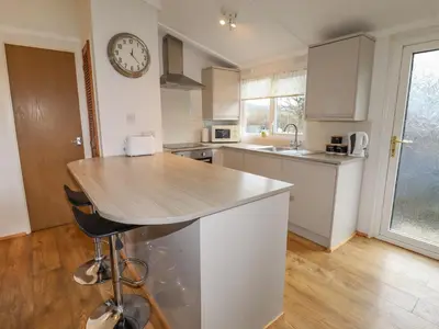 a kitchen with a counter and a clock on the wall at Wayside Lodge in Craven Arms