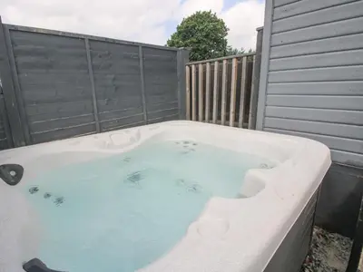 a hot tub in a backyard with a fence at Wayside Lodge in Craven Arms