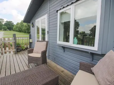 a patio with two chairs and a window on a house at Wayside Lodge in Craven Arms