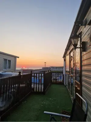 a balcony with a view of the ocean at sunset at Spacious Luxury Escape with Sea Views and Pet Friendly at Clarach Bay in Aberystwyth