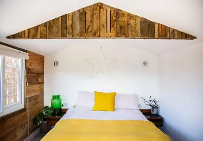a bedroom with a bed with a yellow blanket at The Deckhouse, cabin with big deck nr Hay-on-Wye in Rhos-gôch